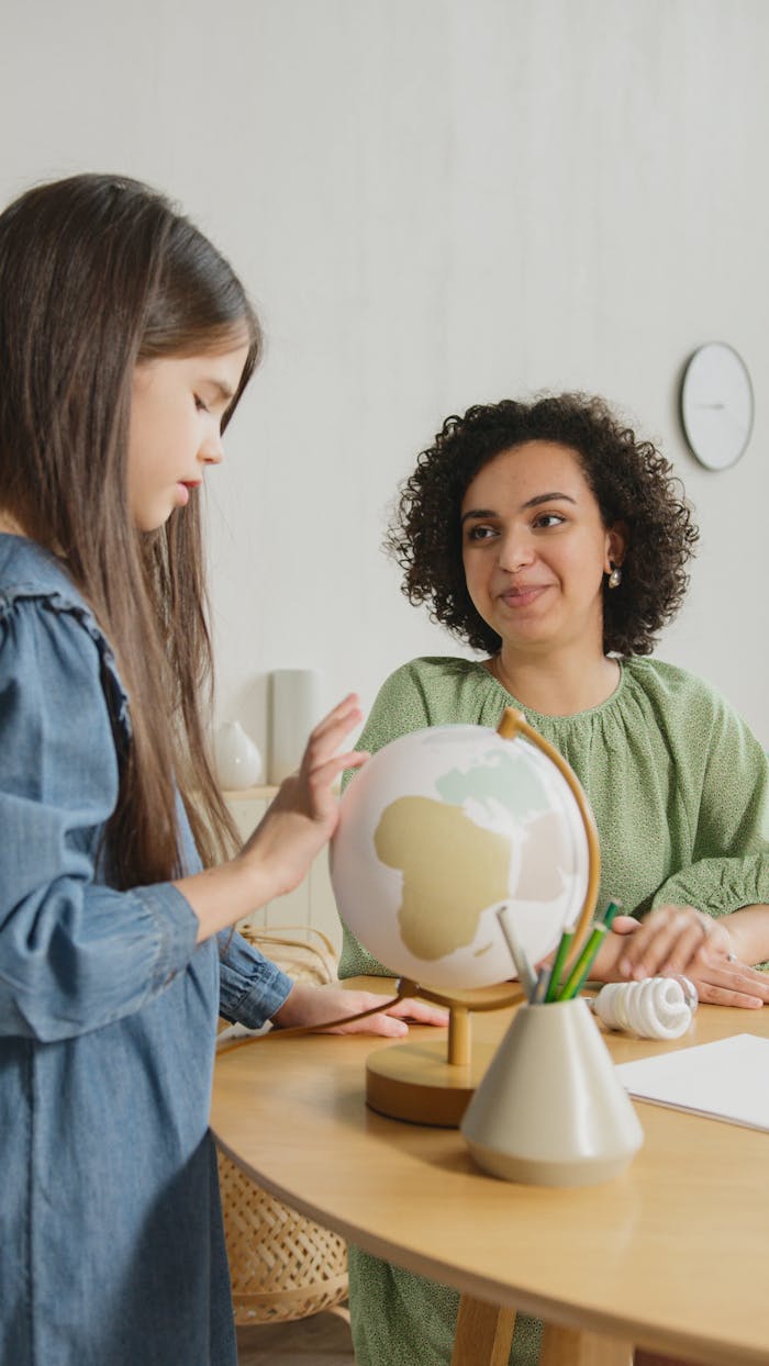 A teacher and student engaged with a globe during a geography lesson in a classroom setting.